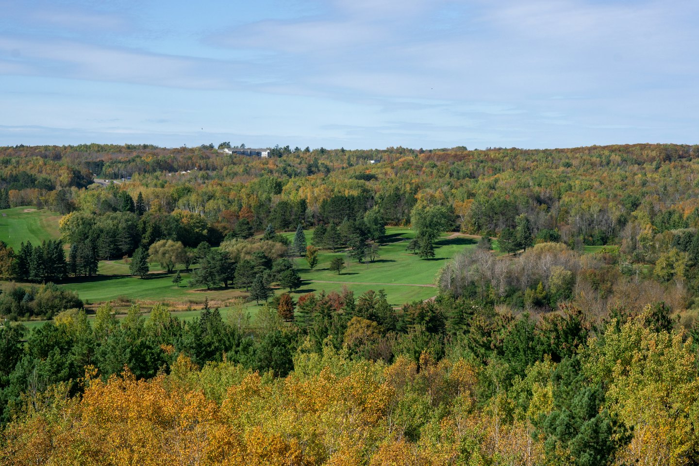 Golf course fairways winding through a colorful autumn forest.